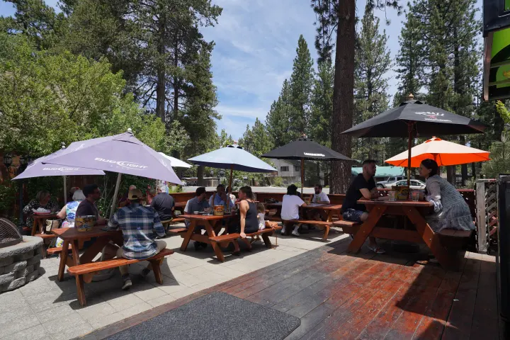A full patio of guests under the umbrellas