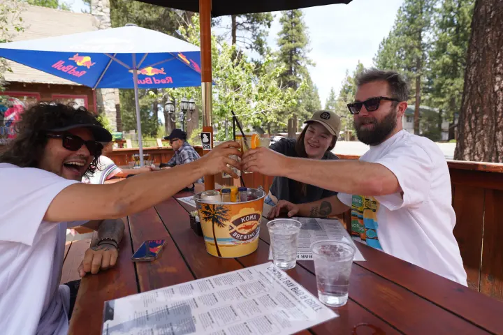 Friends toasting beers at a patio table